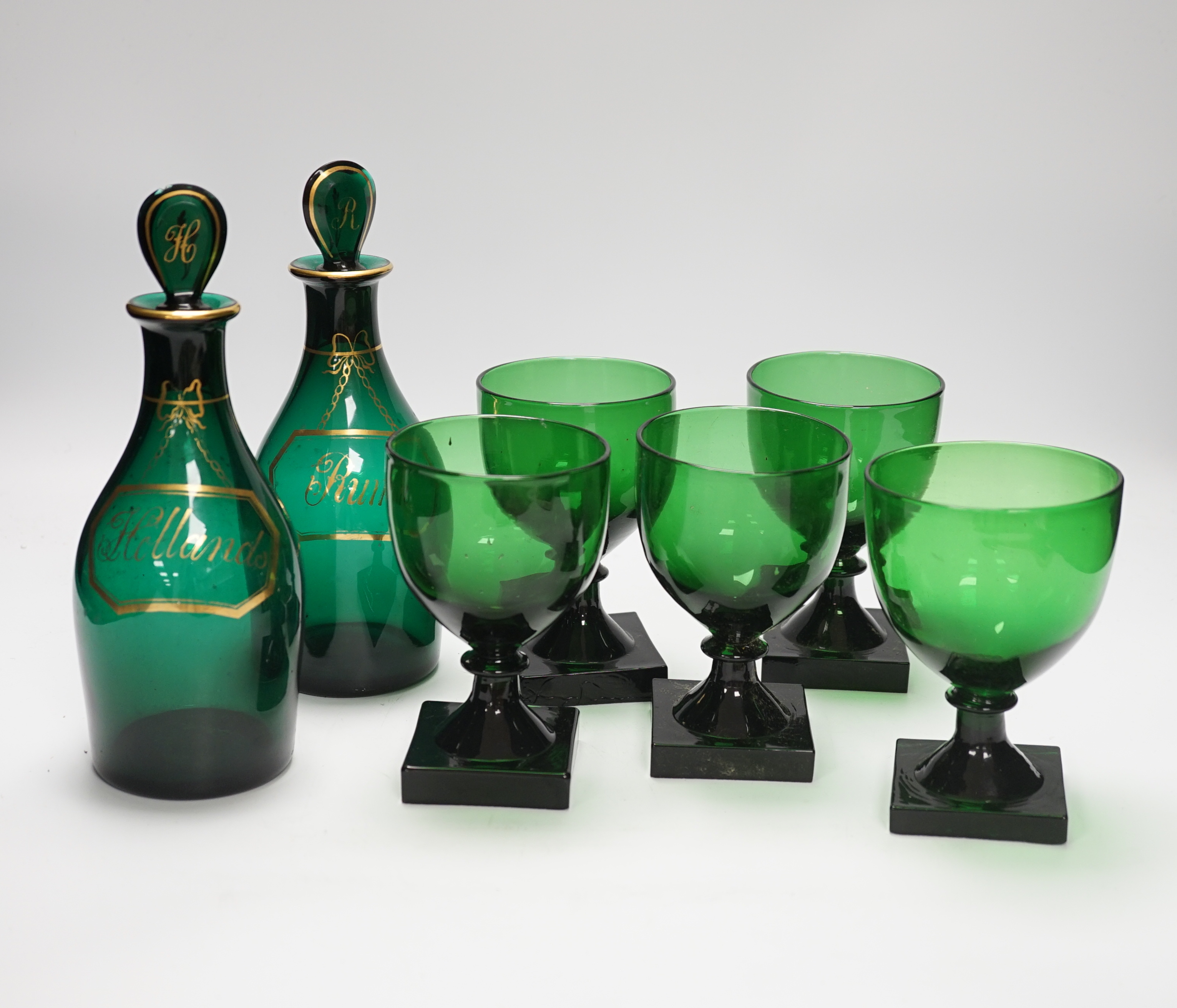 A pair of small Bristol green decanters, Rum and Hollands, c.1800 and five 19th century green glass rummers, with lemon squeezer bases, decanters 22cm high